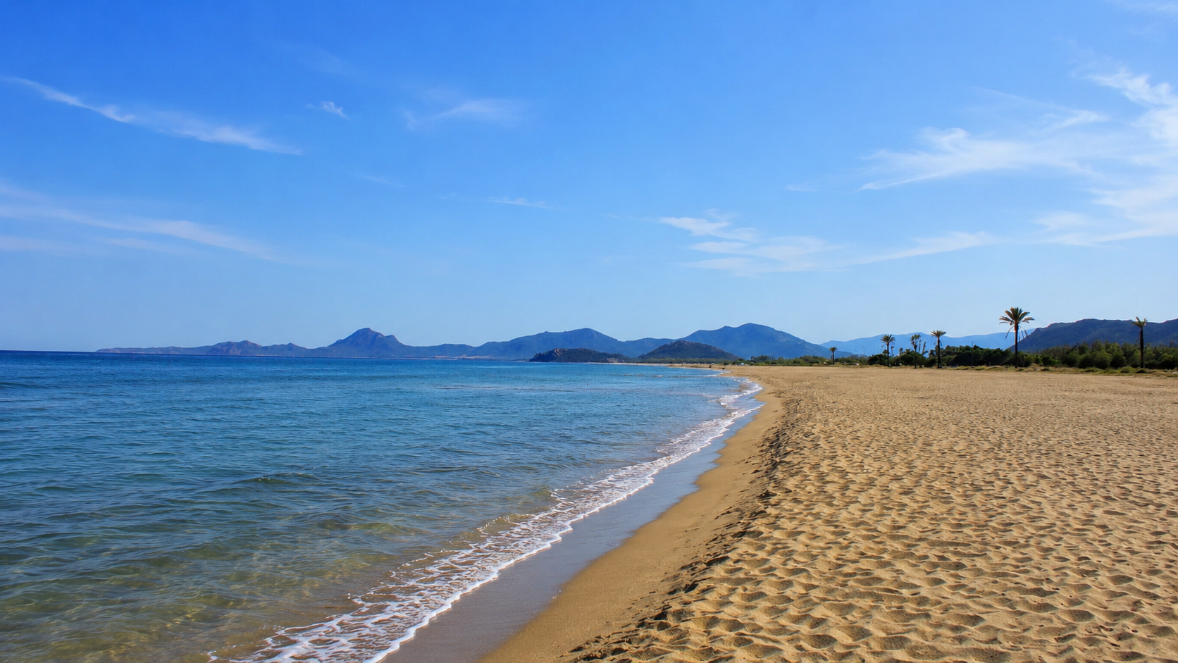 San Giovanni, Muravera — spiaggia dorata di sabbia fine con mare turchese e profilo dei monti sullo sfondo