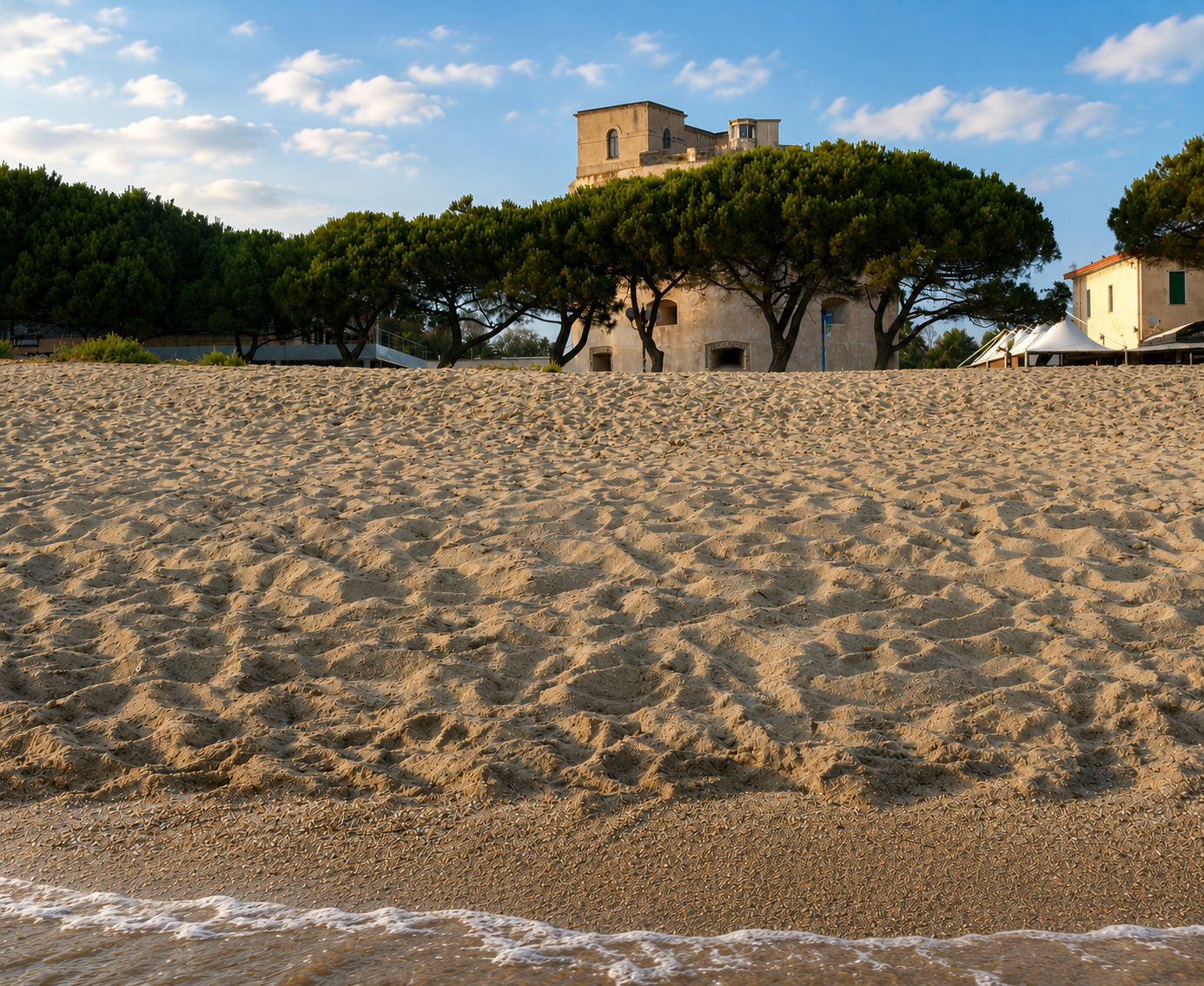 Torre Grande, Oristano — ampia spiaggia di sabbia dorata con pini marittimi e torre spagnola sullo sfondo al tramonto