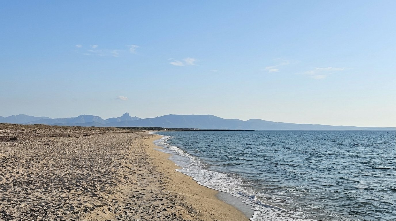Sassu (Abarossa), Santa Giusta — spiaggia dorata con mare azzurro e montagne sullo sfondo