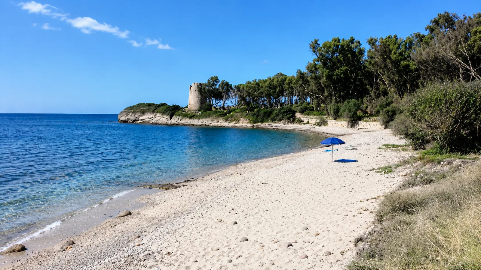 Cala d'Ostia, Pula — piccola cala con torre costiera, pini e acqua azzurra