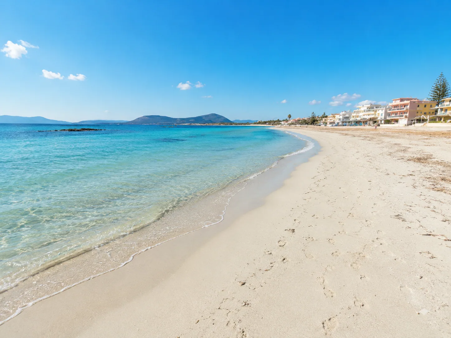 Lido di Alghero — sabbia chiara, acqua turchese e lungomare con palazzine pastello sullo sfondo