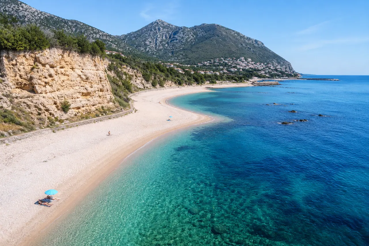 Palmasera, Dorgali — ampia spiaggia di ciottoli bianchi con falesia calcarea e mare trasparente