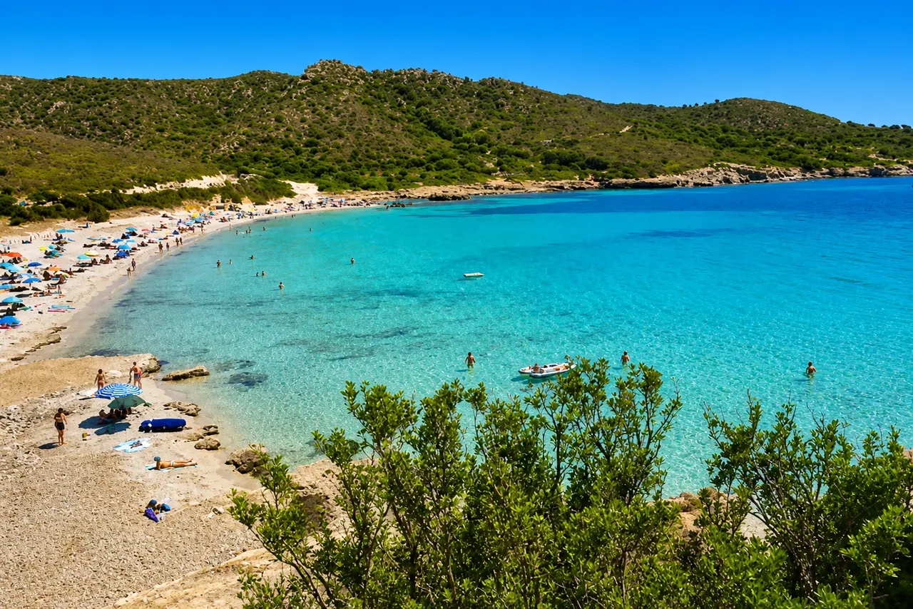 Piscinnì, Teulada — cala riparata con sabbia chiara, acqua turchese cristallina e collina coperta di macchia mediterranea
