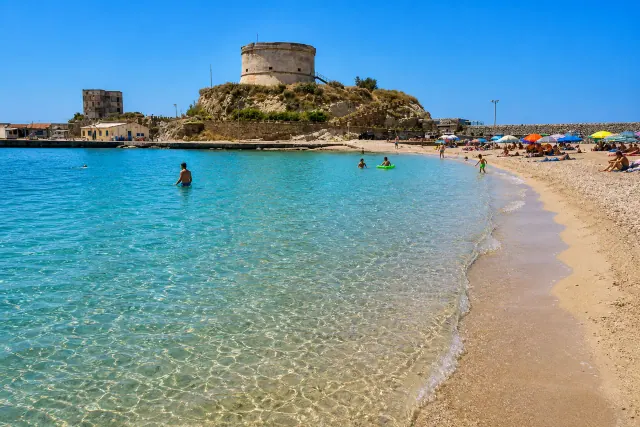 Bosa Marina, Bosa — spiaggia di sabbia chiara con la torre spagnola dell'Isola Rossa sul promontorio e acqua cristallina