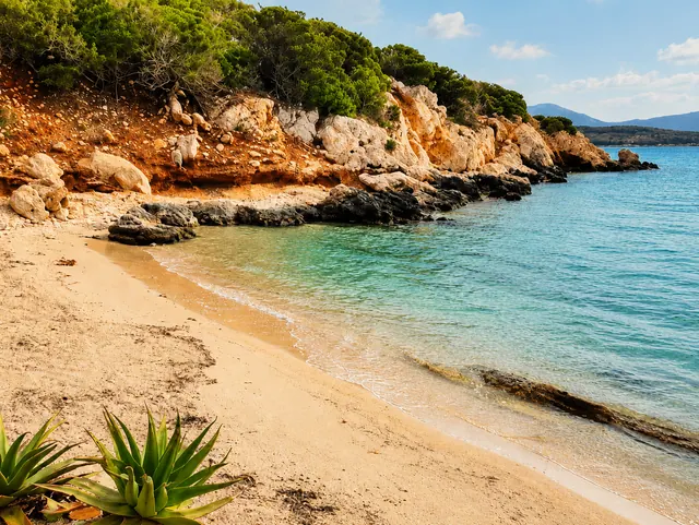 Cala Dragunara, Alghero — piccola cala con sabbia dorata, scogliera chiara e acqua trasparente ai piedi della macchia mediterranea