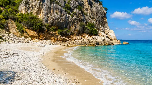 Cala Fuili, Dorgali — mezzaluna di ciottoli alla foce della codula con falesia calcarea e mare cristallino