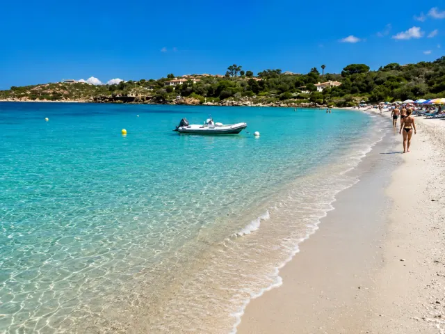 Spiaggia Ira, Olbia — sabbia chiara, acqua cristallina e barca in rada nella baia riparata