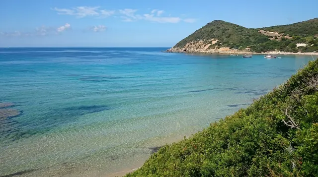 La Speranza (Poglina), Alghero — baia riparata con acqua limpida e fondale chiaro, pendio verde e piccole barche ancorate
