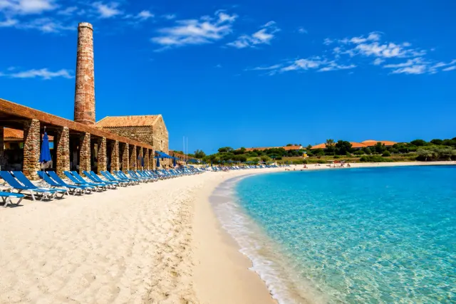 Le Tonnare, Stintino — spiaggia di sabbia chiara con acqua cristallina davanti all'antica tonnara in pietra