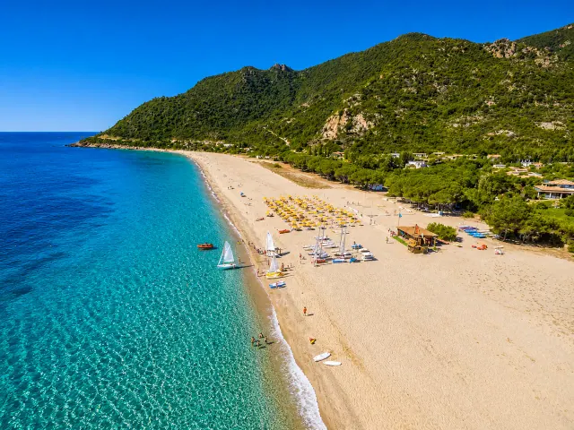 Perd'e Pera, Bari Sardo — lunga spiaggia sabbiosa con ombrelloni gialli, mare cristallino e pineta