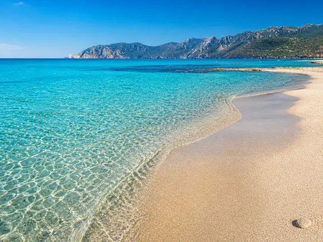 Plagemesu, Gonnesa — battigia chiara e mare trasparente con falesie sullo sfondo