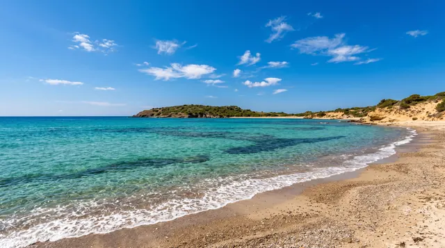 Porto d'Agumu, Pula — arenile misto sabbia e ghiaia con acqua trasparente e promontorio verde sullo sfondo