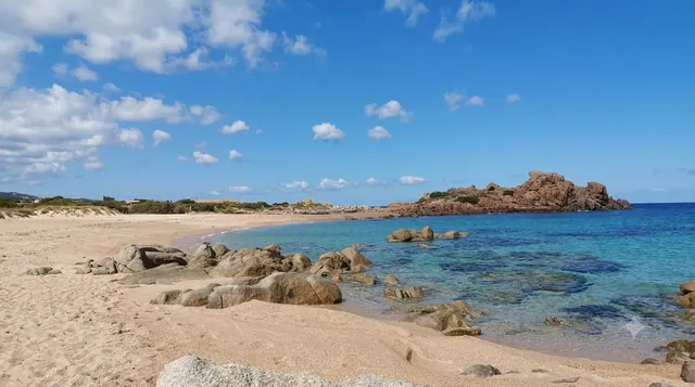 Portobello di Gallura — spiaggia di sabbia chiara con scogli di granito, acqua trasparente e promontorio roccioso sullo sfondo