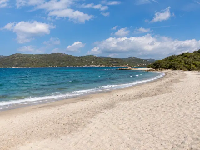 Punta Asfodeli, Olbia — spiaggia ampia di sabbia chiara con mare blu e colline verdi sullo sfondo