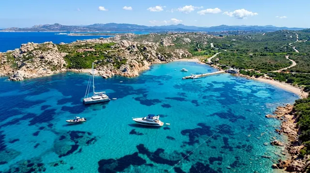 Punta Tegge, La Maddalena — cala turchese tra rocce granitiche con barche ormeggiate e vista aperta verso l'arcipelago
