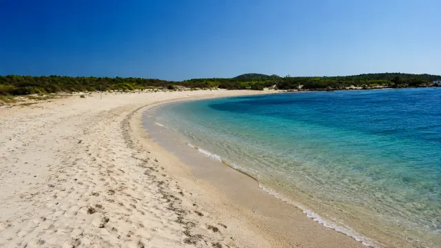 Razza di Juncu, Arzachena — cala riparata di sabbia chiara con acqua turchese cristallina e macchia mediterranea sulle colline