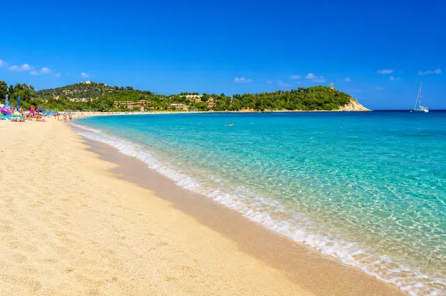 San Gemiliano, Tortolì — spiaggia dorata con acqua trasparente e torre costiera sullo sfondo