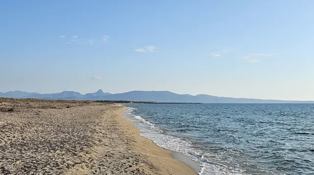 Sassu (Abarossa), Santa Giusta — spiaggia dorata con mare azzurro e montagne sullo sfondo