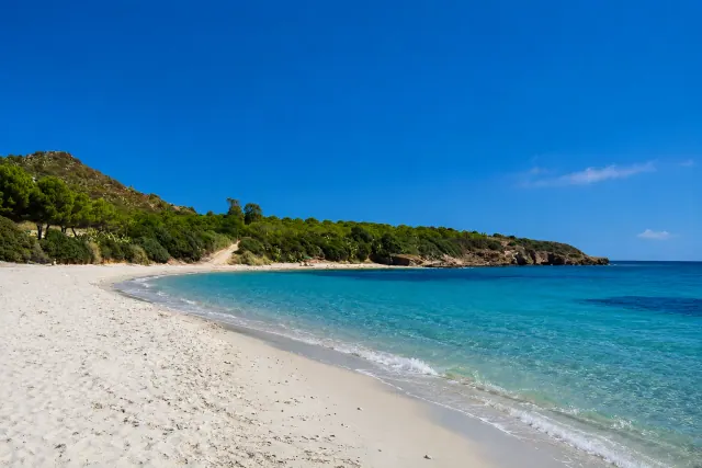 Su Guventeddu, Pula — spiaggia di sabbia bianca con mare turchese e promontorio verde