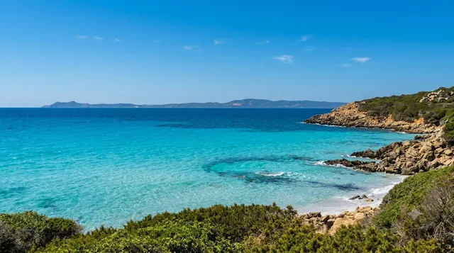 Su Portu de su Trigu, Sant'Anna Arresi — cala rocciosa con acqua turchese cristallina, macchia mediterranea e costa sullo sfondo